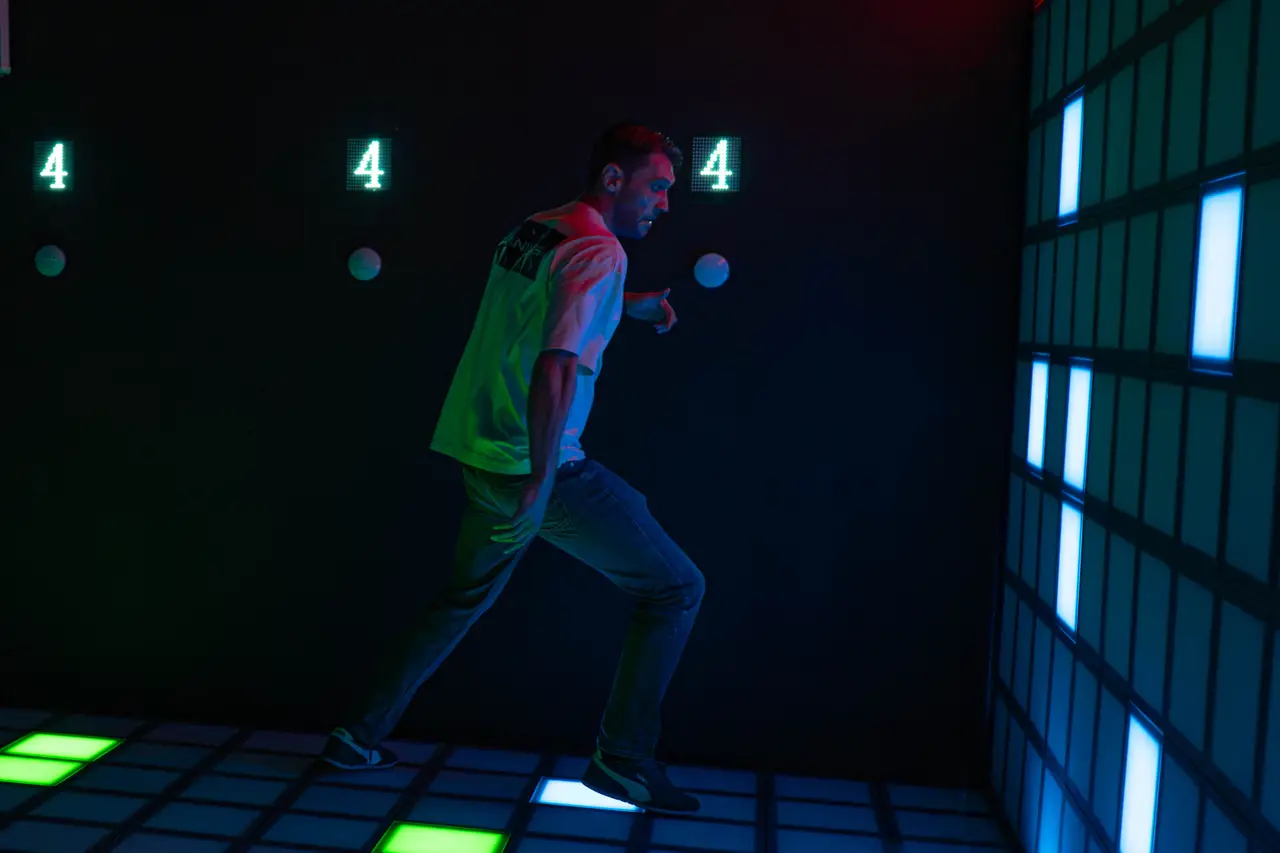 Participant interacționând cu podeaua LED și panourile luminoase de perete
